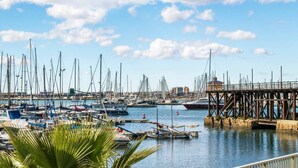 Un port de plaisance où sont amarrés de nombreux bateaux, une jetée et un ciel dégagé.