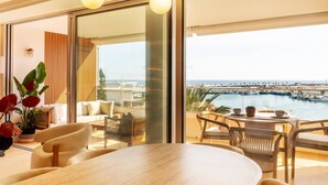 Un salon moderne doté d’une grande fenêtre, d’un coin repas et offrant une vue sur un port de plaisance.