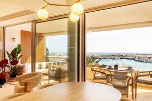 Ein modernes Wohnzimmer mit einem großen Fenster, einem Essbereich und Blick auf eine Marina.