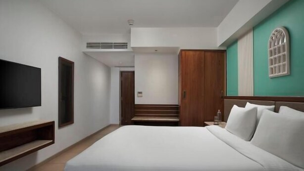 A hotel room with a bed, a TV, a wooden wardrobe, and a staircase leading to another room.