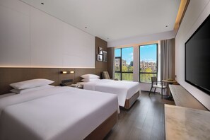A hotel room with two beds, a desk, a chair, a TV, and a window with a city view. - Garden Resort Kunming Changshui Airport (Kunming)