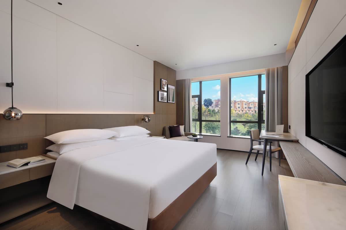 Et moderne hotelværelse med en stor seng, et skrivebord og et fjernsyn.