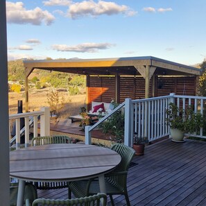 A wooden deck with a covered seating area, outdoor furniture, and potted plants.