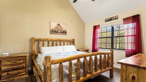 A wooden bed with a headboard, a bedside table, and a window with curtains. - Smoky Ridge Retreat | Hot Tub • Firepit • Views (Gatlinburg)