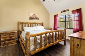A wooden bed with a headboard, a bedside table, and a window with curtains.