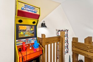 A room with a wooden railing, a wall-mounted TV, and a lamp.