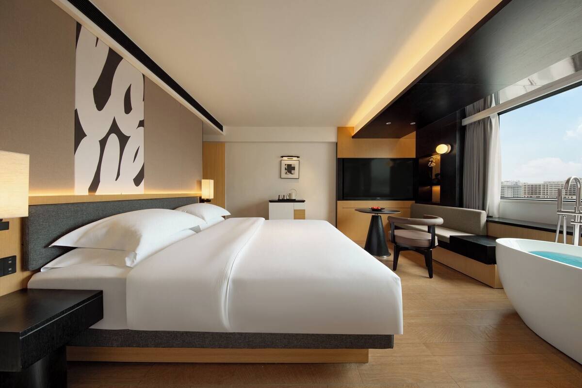 Une chambre d’hôtel moderne équipée d’un grand lit, d’un bureau, d’une chaise, d’une télévision et d’une baignoire.