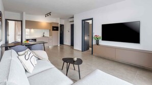 Un soggiorno moderno con un divano, un tavolino e una TV a parete.