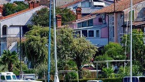Una marina con barche ormeggiate, una chiesa con un campanile e edifici residenziali sullo sfondo.