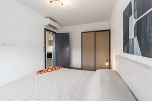 A modern hotel room with a bed, wardrobe, and a large abstract painting on the wall. - Holiday apartment modernly furnished with full equipment (Funtana)