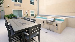 Eine Terrassenanlage im Freien mit Esstisch, Stühlen, Grill und kleinem Pool.