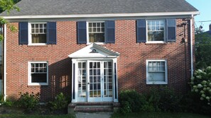 A two-story brick house with a central entrance, a small porch, and a covered front porch. - Lux Colonial Home: Hot tub, Game Room, Home Theatre, Karaoke (Framingham)