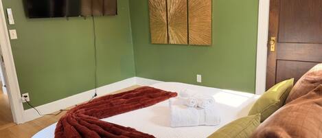 Una habitación con una cama, un televisor de pared y un panel decorativo.