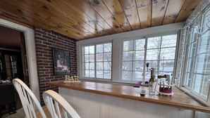 Una cocina con techo de madera, pared de ladrillo y ventana con vistas a un paisaje nevado.