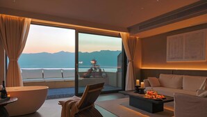 Une chambre d’hôtel moderne dotée d’une grande porte-fenêtre coulissante donnant sur un balcon, d’un canapé, d’une table basse et d’une plante décorative.