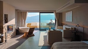Une chambre d’hôtel moderne dotée d’une grande porte-fenêtre coulissante donnant sur un balcon avec vue sur la mer.