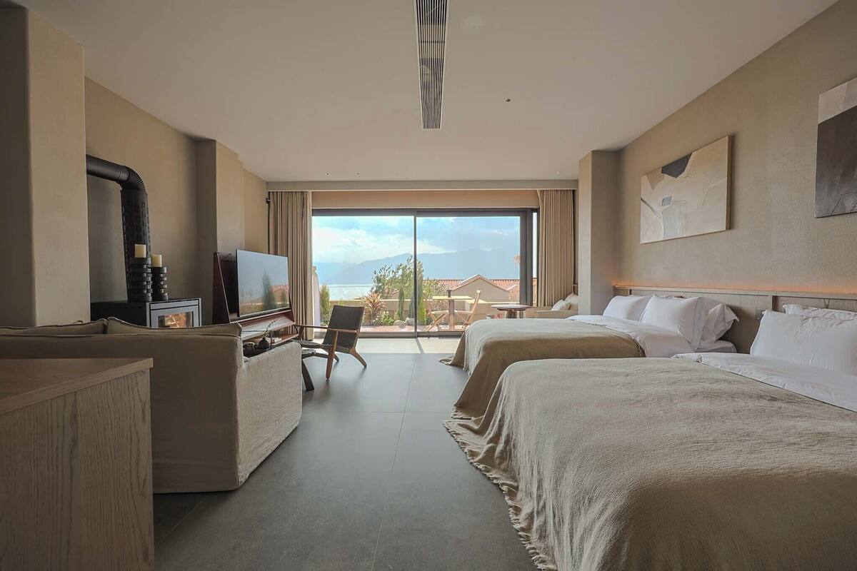 A hotel room with a bed, a desk, a chair, a television, and a large window with a view.