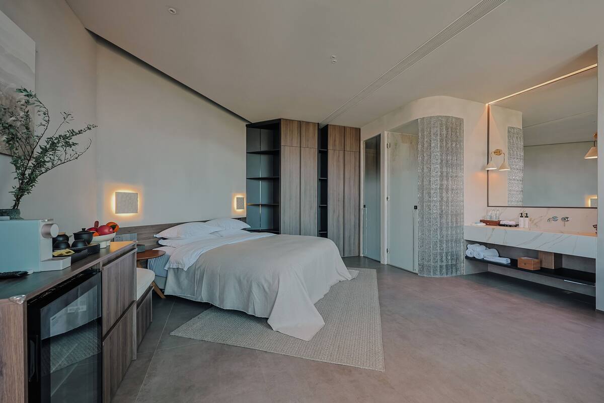A modern bedroom with a bed, bedside table, and a large mirror.