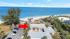 An aerial view of a coastal property with a parking lot, a building with a flat roof, and a beach in the background. - Venice Villas San Marco - Oceanfront - Beach (Venice)