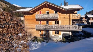 Un chalet en bois doté d’un balcon, d’un toit enneigé et surplombant un paysage montagneux.