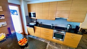 Une cuisine moderne avec des meubles en bois, un plan de travail noir et un four en acier inoxydable.