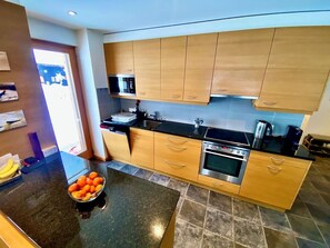 Une cuisine moderne avec des meubles en bois, un plan de travail noir et un four en acier inoxydable.