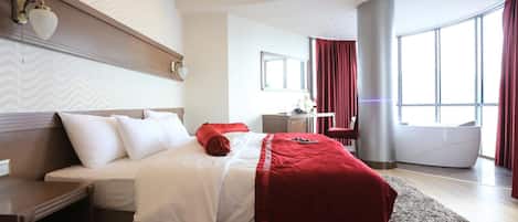 Quarto de hotel moderno com uma cama grande, uma escrivaninha e vista para a cidade.