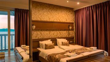 Een hotelkamer met een groot bed, een houten hoofdeinde, een nachtkastje en uitzicht op zee.