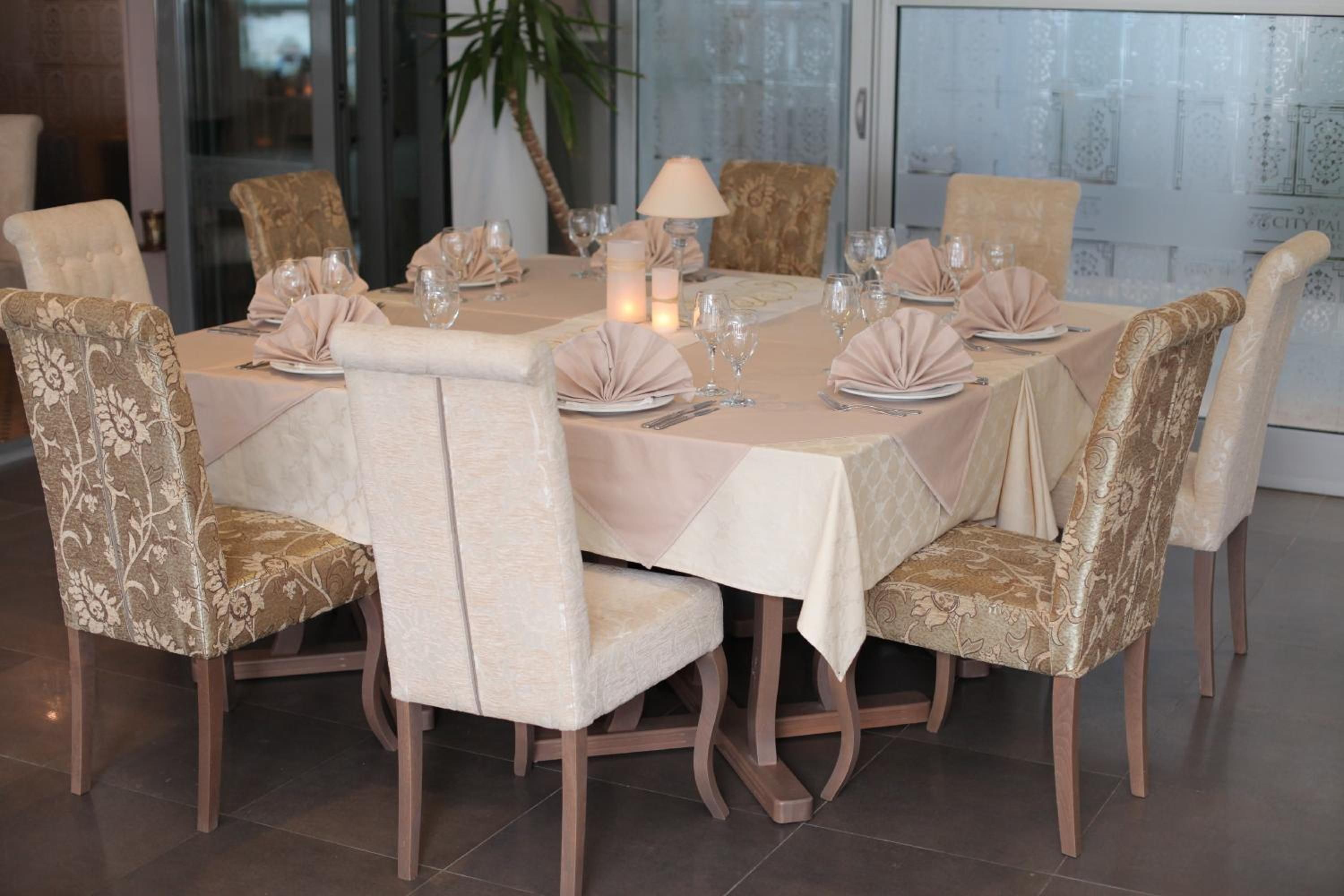 A dining area with a round table set for six, surrounded by upholstered chairs with a floral pattern.