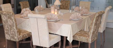 A dining area with a round table set for six, surrounded by upholstered chairs with a floral pattern.