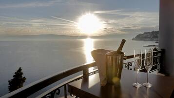 Una mesa con una botella y copas, con vista a un cuerpo de agua al atardecer.