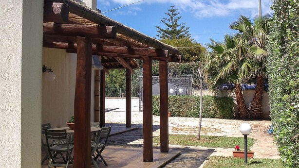 A covered patio area with a table and chairs, a stone pathway, and surrounding greenery. - Pet friendly home in Marsala with house sea view (Marsala)