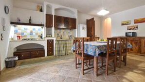 A kitchen with a dining area, a tiled backsplash, wooden cabinets, and a table with chairs. - Pet friendly home in Marsala with house sea view (Marsala)