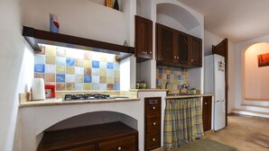 A kitchen with a gas stove, tiled backsplash, wooden cabinets, and a refrigerator. - Pet friendly home in Marsala with house sea view (Marsala)