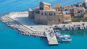 An aerial view of a coastal town with a prominent castle, a harbor with boats, and a fortified wall. - 2 bedroom lovely home in Castellammare del Golf (Castellammare del Golf)
