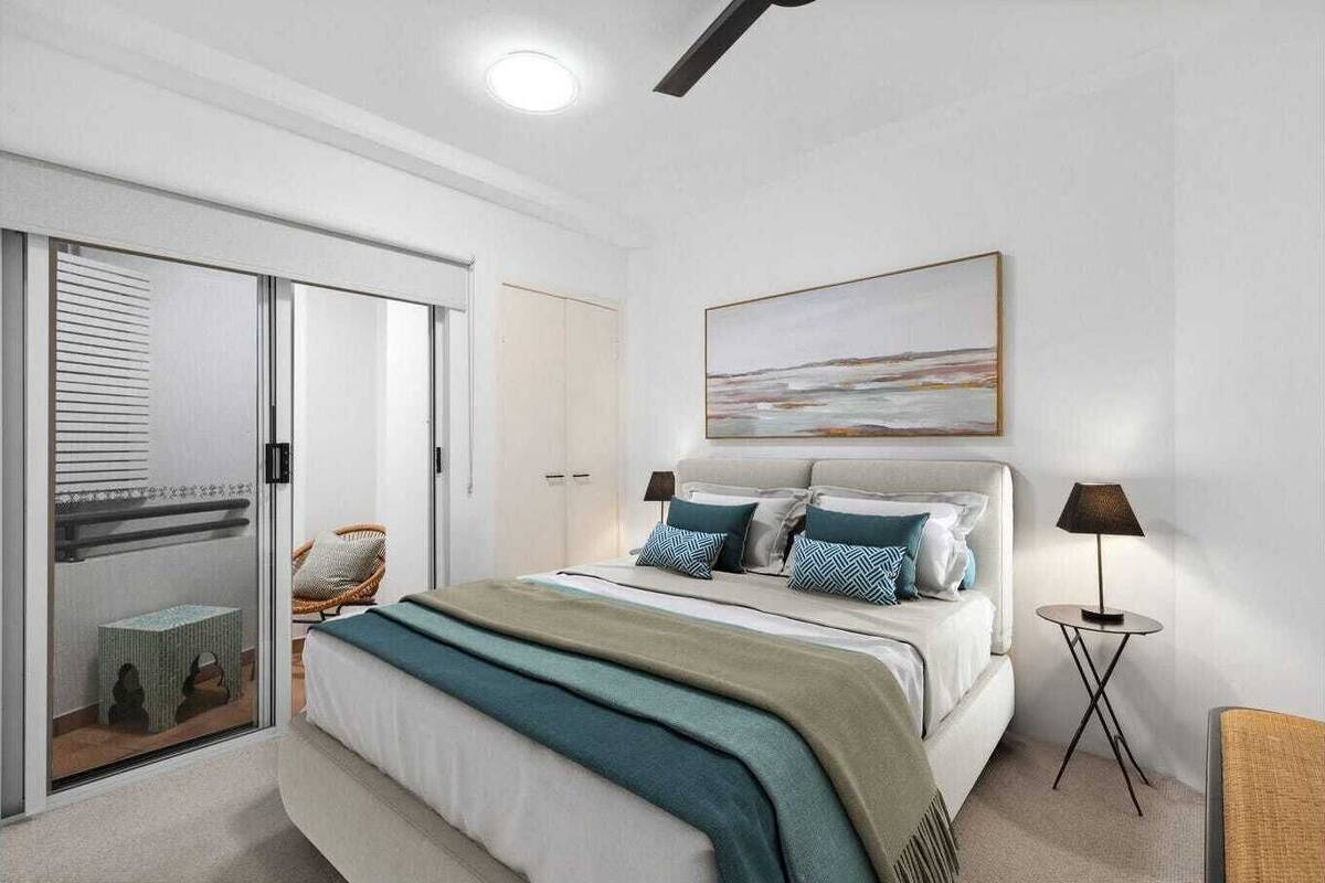 A bedroom with a bed, a chair, a bedside table, a lamp, and a painting on the wall.
