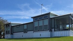 A modern two-story building with large windows and a covered porch area. - Riverfront Property with Direct Access & Private Pier (Robstown)