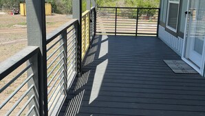 A covered porch with a metal railing, a welcome mat, and a view of the surrounding landscape. - Riverfront Property with Direct Access & Private Pier (Robstown)