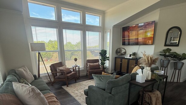 A spacious living room with a large window, a ceiling fan, and a flat-screen TV mounted on the wall. - Riverfront Property with Direct Access & Private Pier (Robstown)