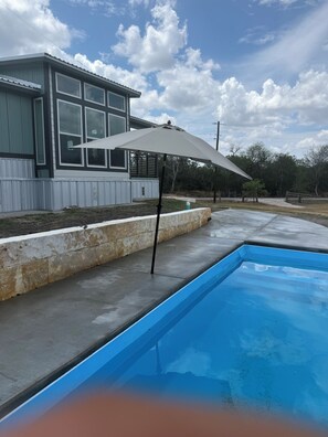 A swimming pool with a concrete deck, a house with large windows, and a cloudy sky. - Riverfront Property with Direct Access & Private Pier (Robstown)