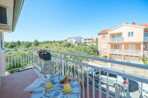 A balcony with a table set for breakfast, a car parked in the background, and buildings in the distance. - Holiday Apartment Angie Suite 2+2 (Vodice)
