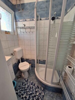 A bathroom with a toilet, shower, and a small rug. - Holiday Apartment Angie Suite 2+2 (Vodice)