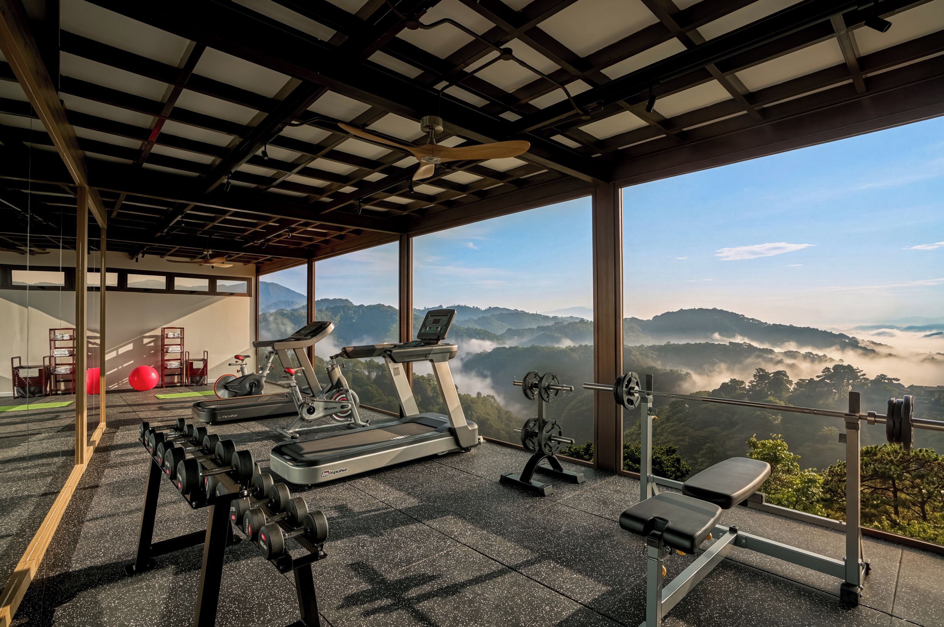 Une salle de sport équipée de matériel d’exercice, d’un tapis de course et d’un banc.