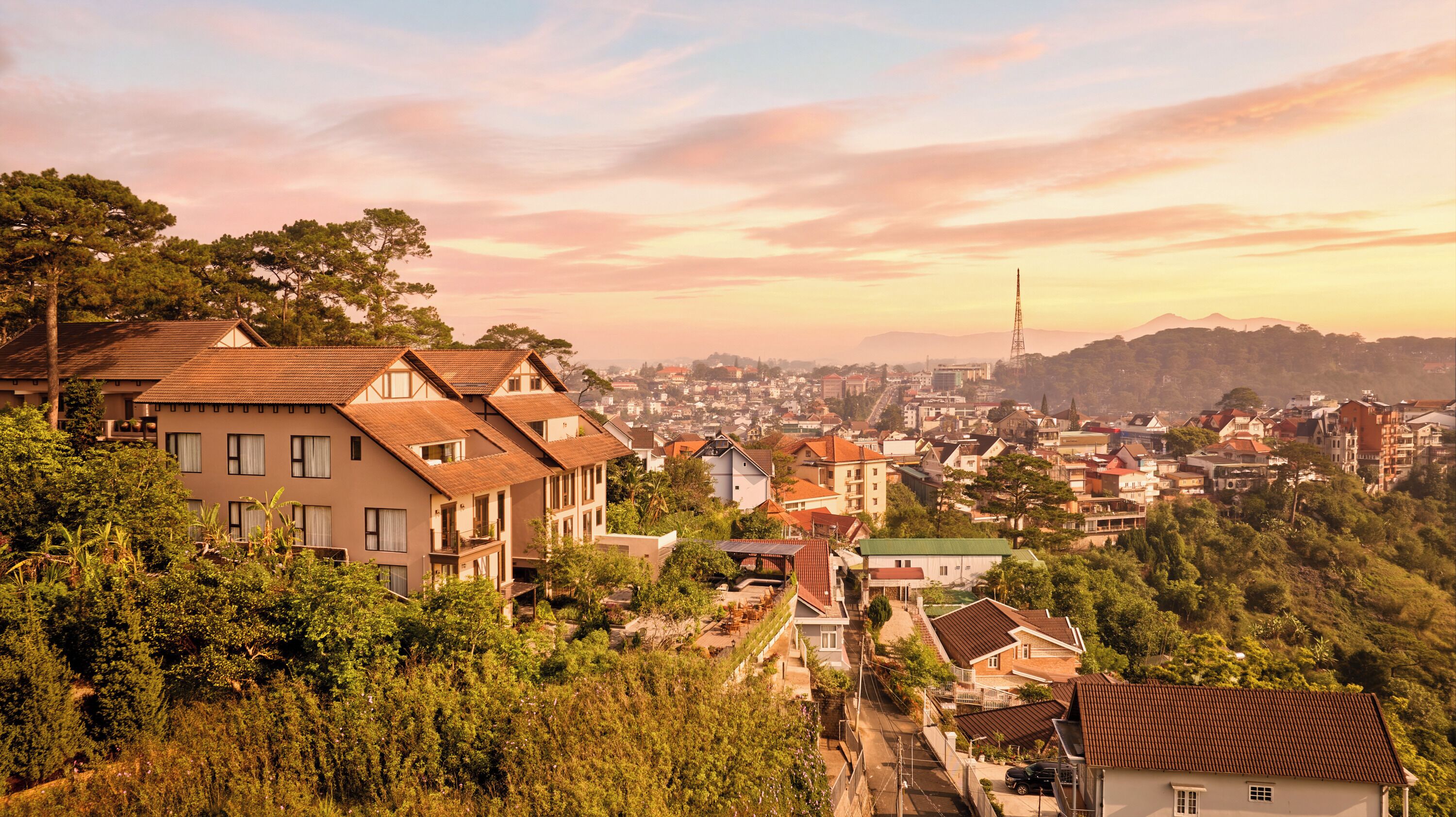 A residential area with houses, a prominent tower, and a hilly backdrop.