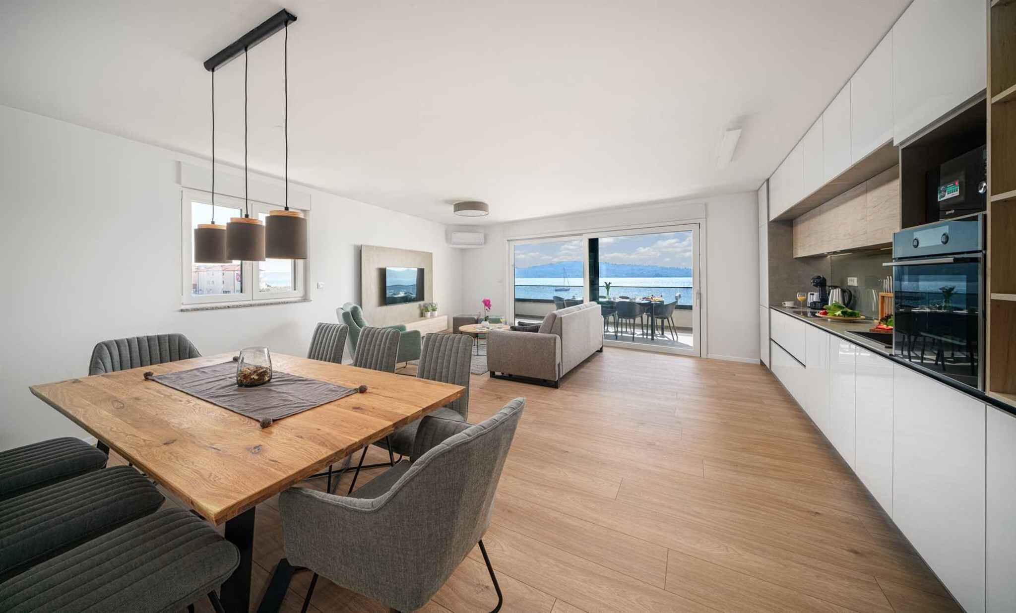 Un apartamento moderno con comedor, cocina y un balcón con vista al mar.