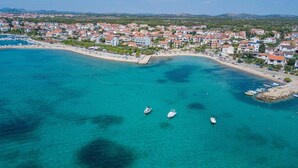 An aerial view of a coastal town with a marina, clear turquoise waters, and a densely packed residential area with red-roofed buildings. - Holiday Apartment Sabbia 6+0 (Srima)