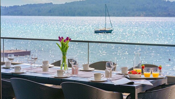 A dining table with a view of the sea, a sailboat, and a mountain in the background. - Holiday Apartment Sabbia 6+0 (Srima)