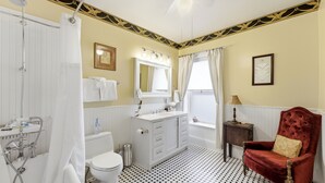 A bathroom with a shower, toilet, vanity, and a red chair. - Comfortable Victorian style 1-br in Boutique B&B. (Heber City)