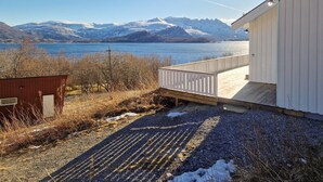 Een chalet met terras, met uitzicht op een meer en bergen.