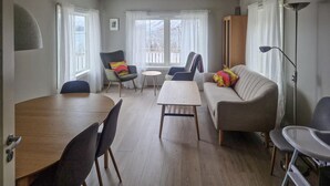 Een moderne woonkamer met een houten eettafel, twee banken, een klein rond tafeltje en een vloerlamp.